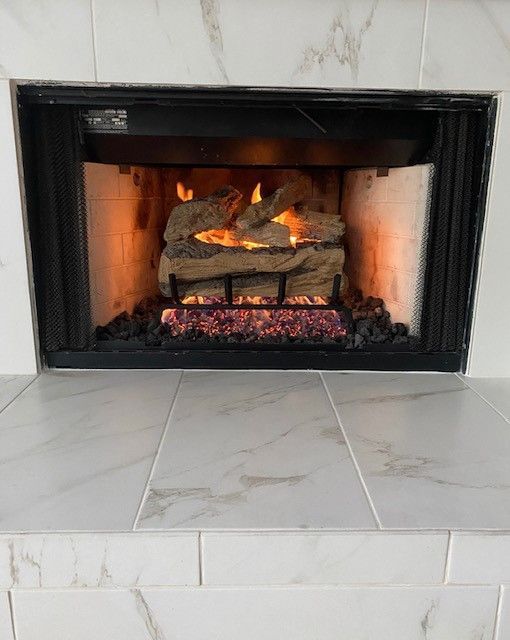 Modern black fireplace with burning logs and glowing embers set in a white tiled surround