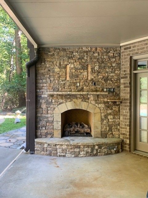 Covered patio with stone fireplace, arched opening, and concrete floor