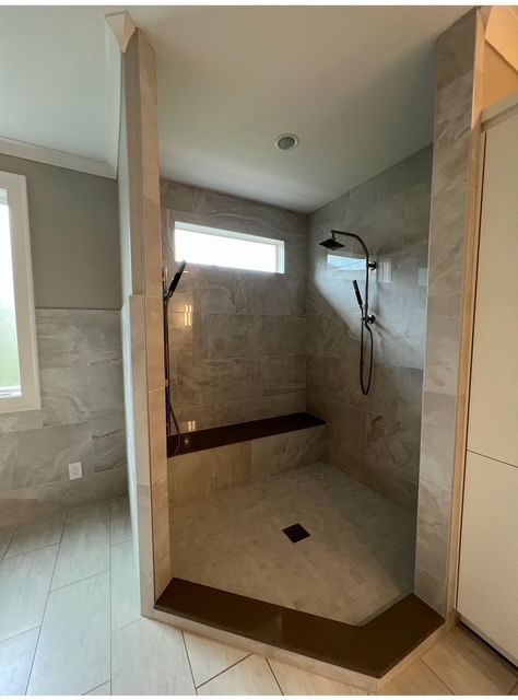 Modern walk-in shower with beige tile, two showerheads, and a small high window