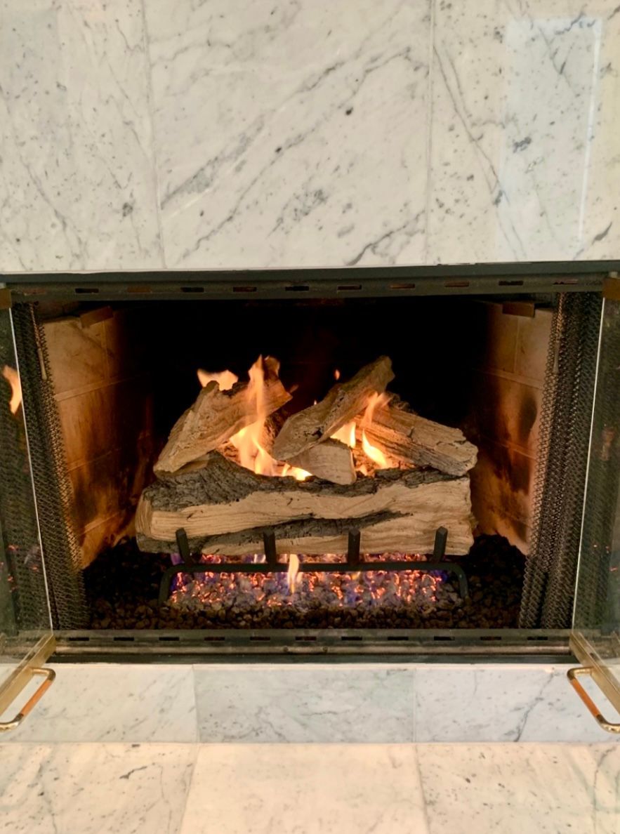 Lit fireplace with burning logs in a marble surround