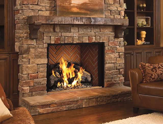 Cozy living room with a stone fireplace burning bright orange flames, leather chair, and warm wood accents