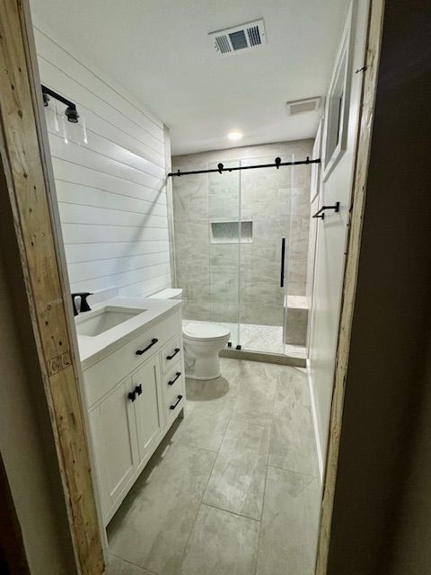 Bright bathroom with white vanity, tiled walk-in shower, and light gray floor.