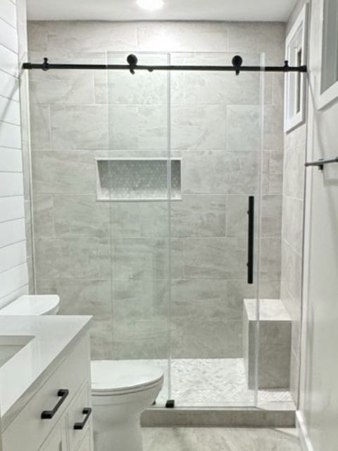 Modern bathroom with glass shower, wall niche, and black hardware