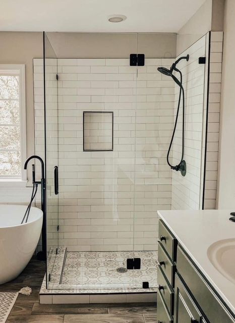 Modern bathroom with walk-in tiled shower, black fixtures, and white vanity.