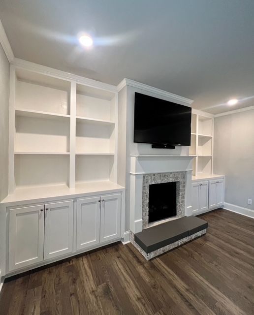 Built-in white cabinetry and fireplace with a mounted TV in a modern living room with wood flooring