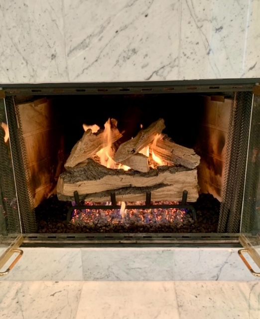 Lit fireplace with burning logs and glowing embers inside a marble surround