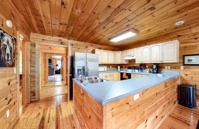 Wood-paneled kitchen with white cabinets, stainless fridge, and light blue countertop island.