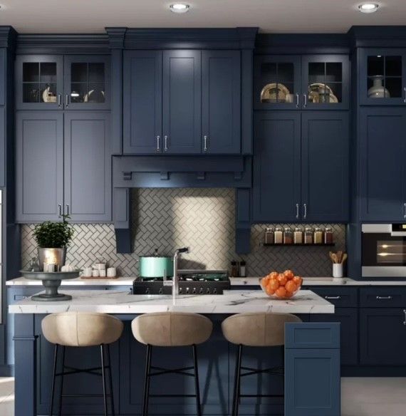 Dark navy kitchen with marble island, beige stools, and stainless appliances