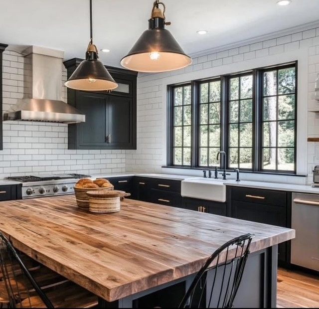 Modern kitchen with black cabinets, white tile, large island, pendant lights, and a wide window