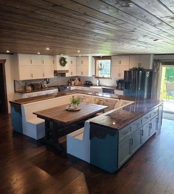 Spacious rustic kitchen with white cabinets, dark wood island, and open layout with large windows