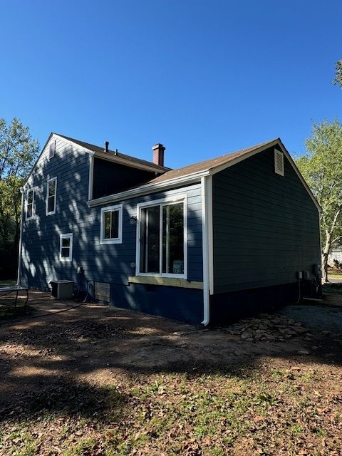 Blue house with white trim and large windows, viewed from the side on a sunny day.