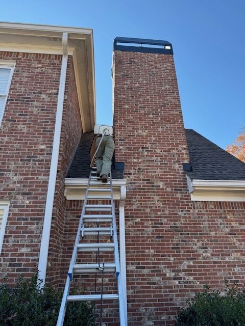 Worker on a ladder repairing a brick chimney on a house