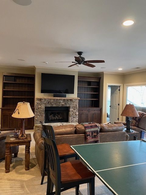 Living room with stone fireplace, TV, built-in shelves, sectional sofa, and ping-pong table in foreground