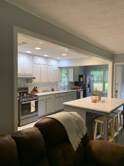 Open kitchen and dining area with white cabinets, gray lower cabinets, island, and sliding glass doors to outside.