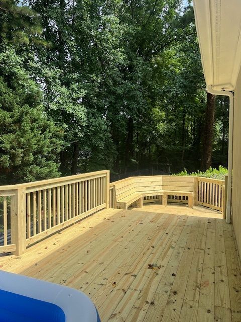 Wooden deck with railings overlooking a wooded backyard, with a blue chair in the foreground.