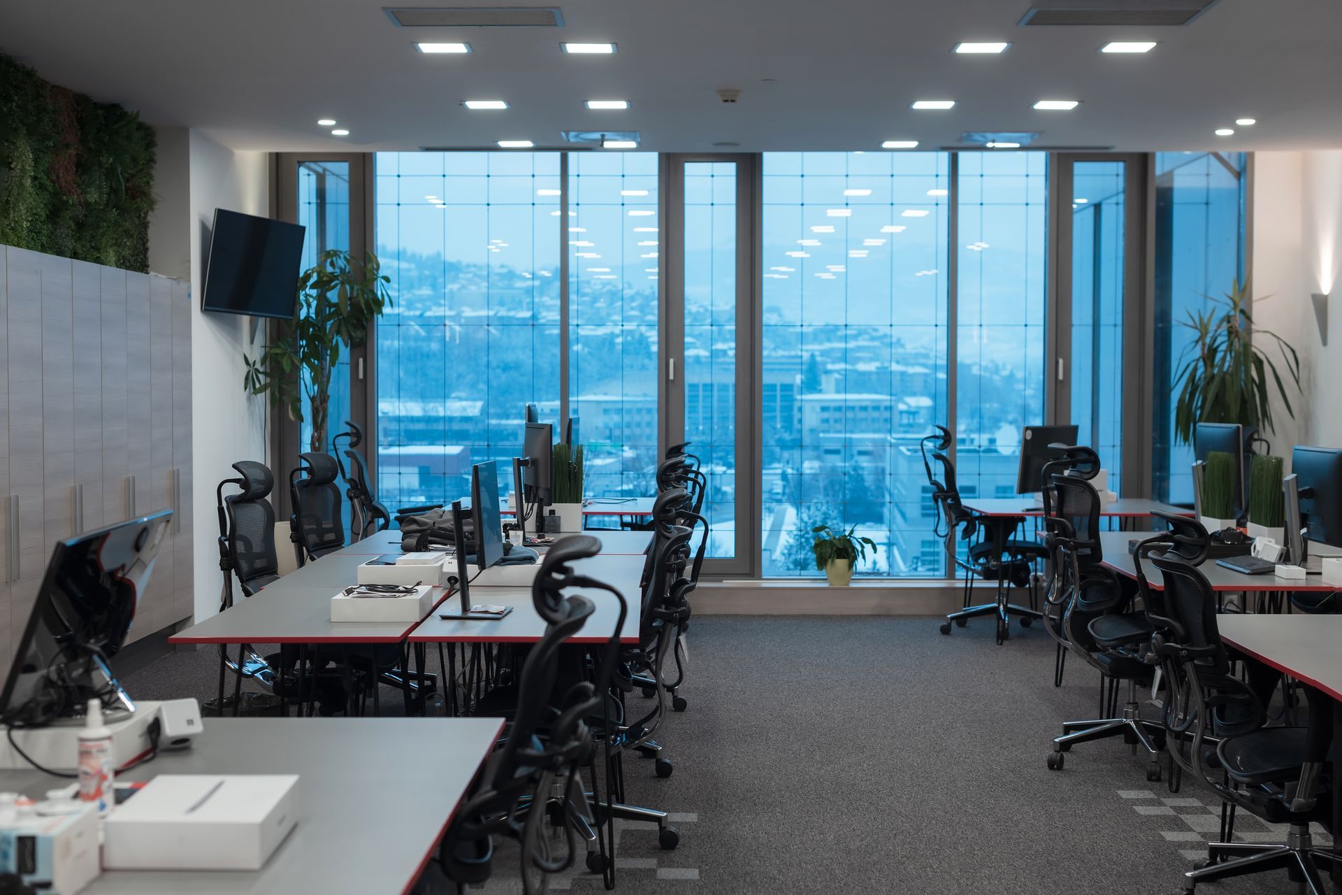 Office cleaners mopping a wet floor around desks and computers in a bright workspace