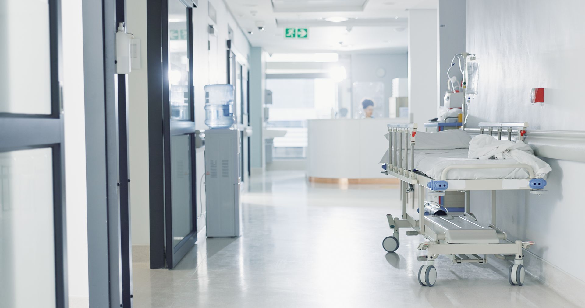 Bright hospital corridor with an empty baby bassinet and medical equipment on the right