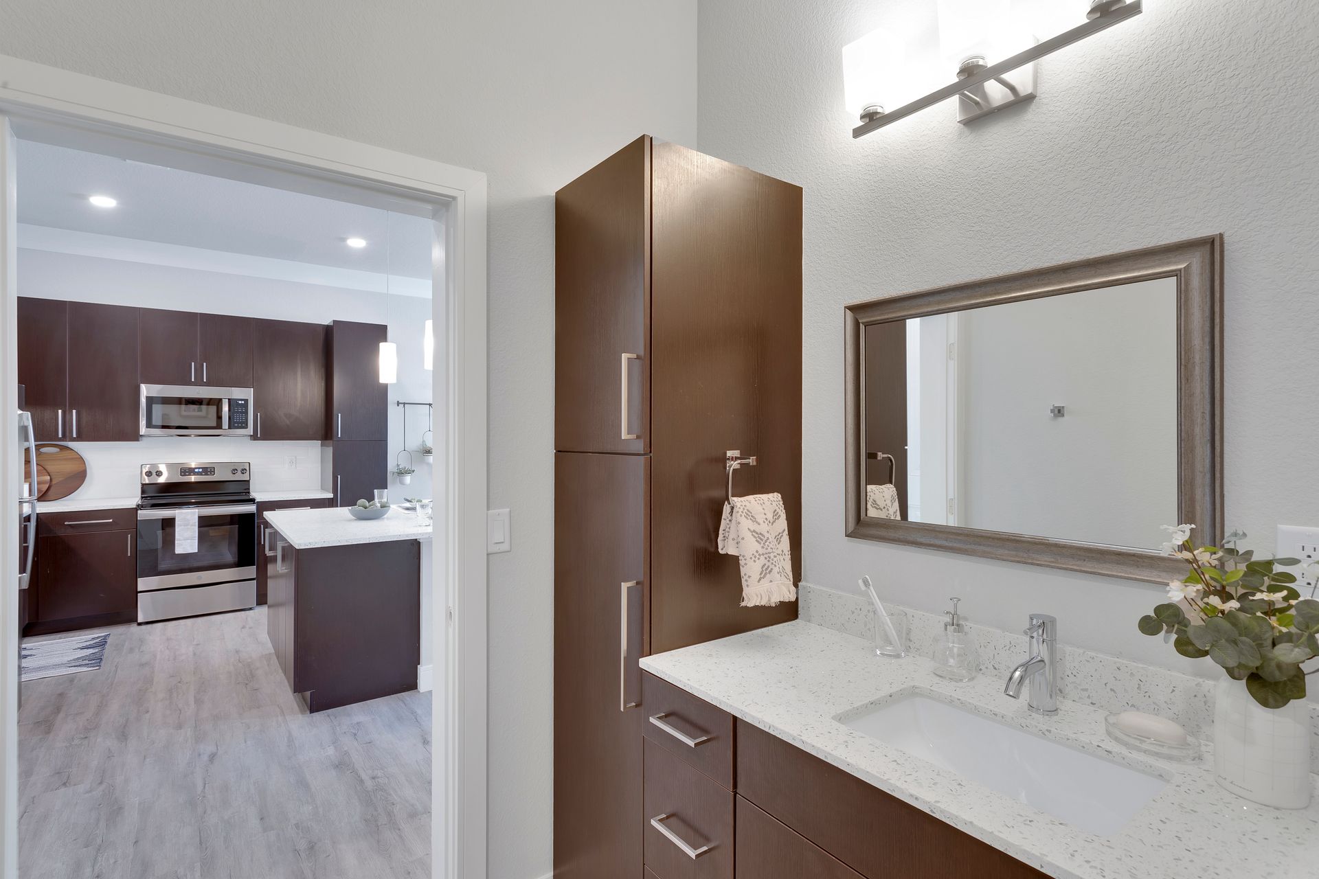 Modern bathroom vanity with mirror and doorway to a kitchen beyond