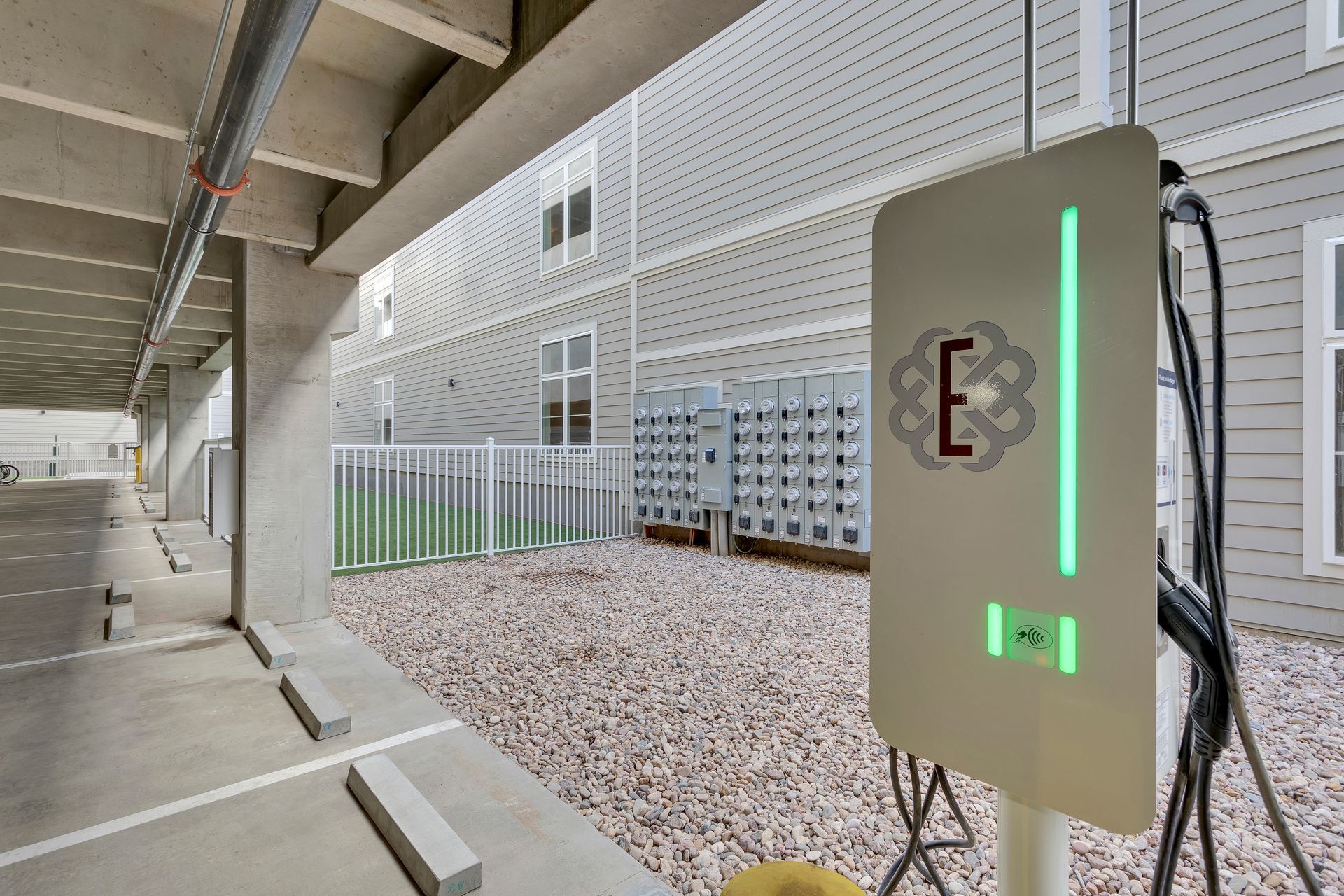 Outdoor EV charging station under a covered structure, with a glowing green charger in the foreground.