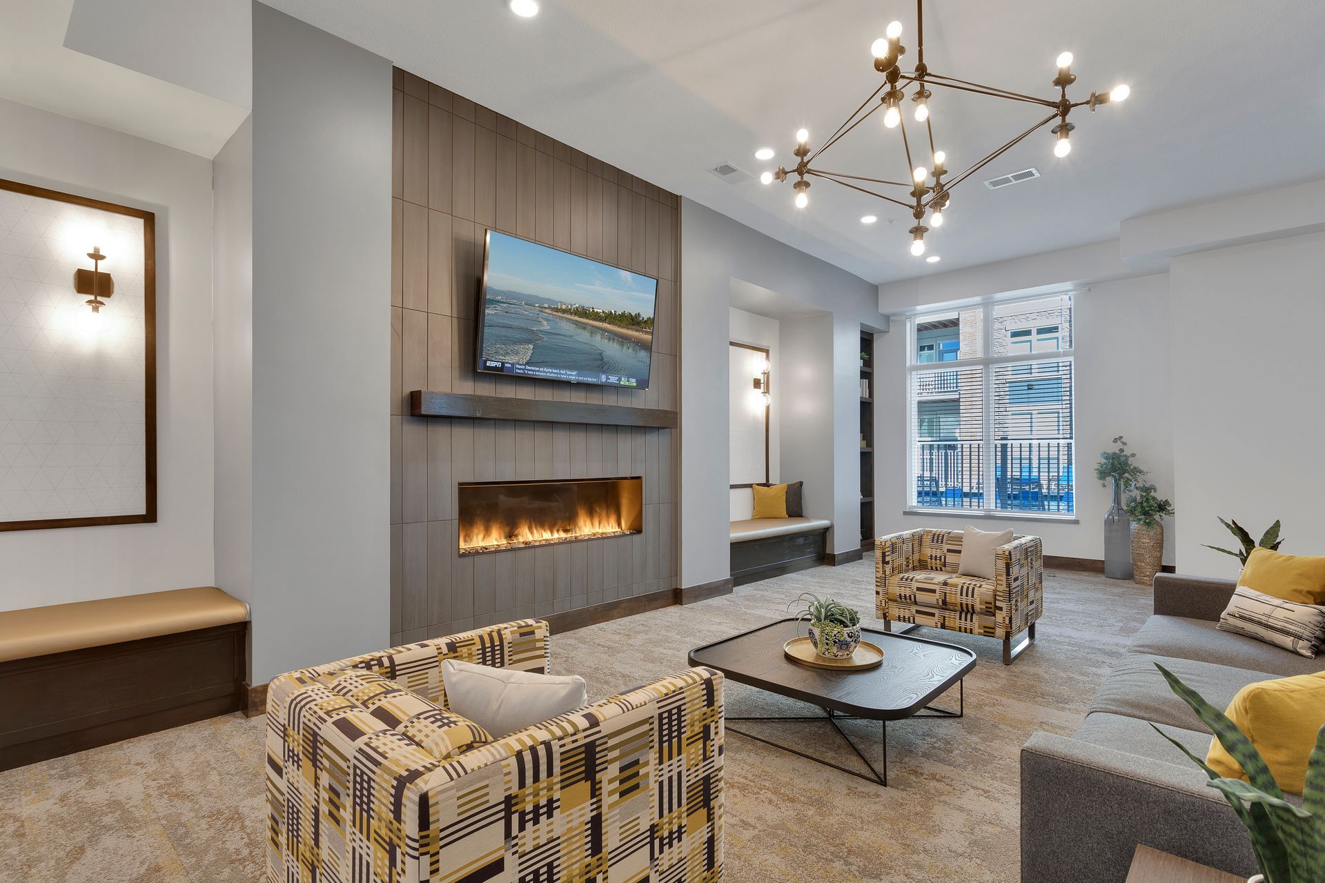 Modern living room with fireplace, wall-mounted TV, chandelier, and large windows
