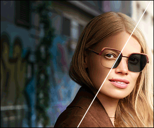 Woman with glasses and a brown coat, half-lit in front of a graffiti wall
