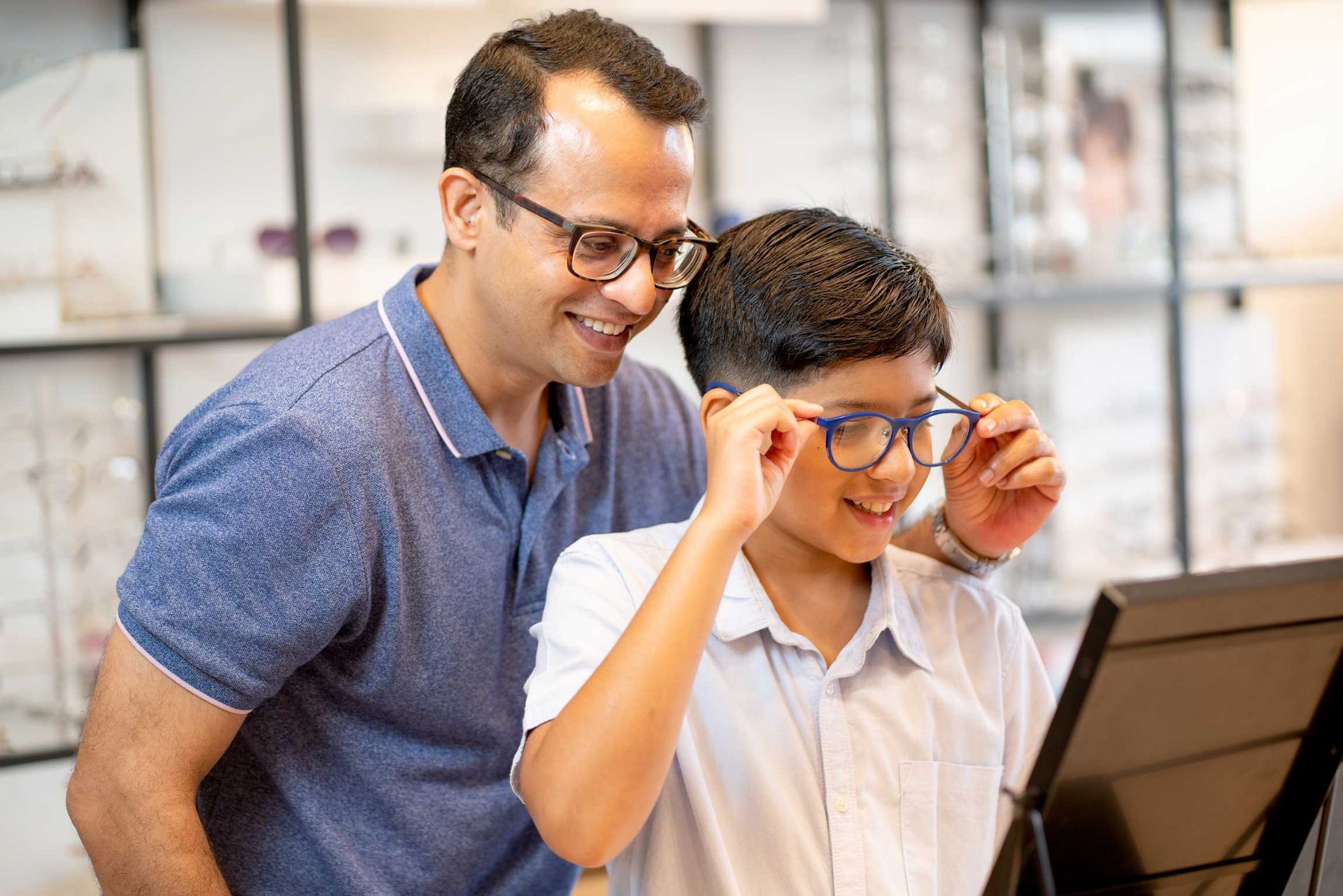 Man and boy smiling while looking at a laptop in an office