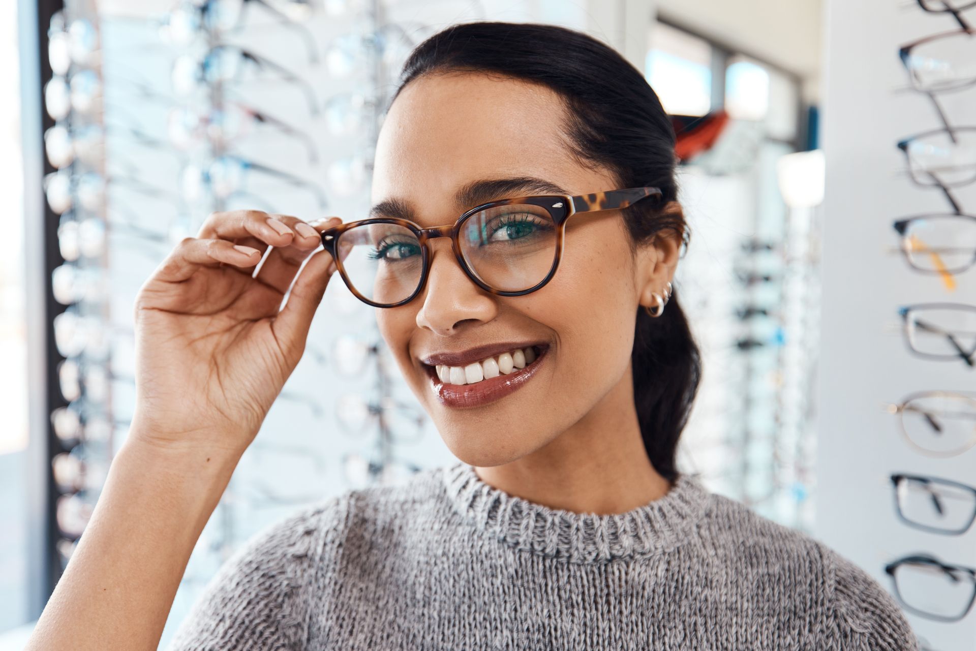 Woman smiling while trying on eyeglasses in an optical store