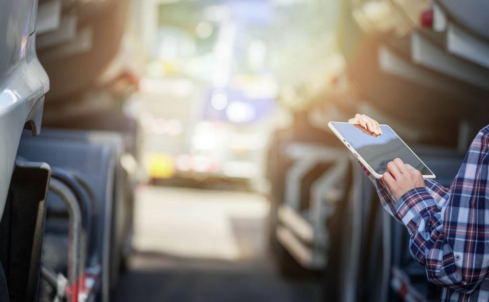 Passenger holding a tablet on a bus, seated by the window with sunlight streaming in.
