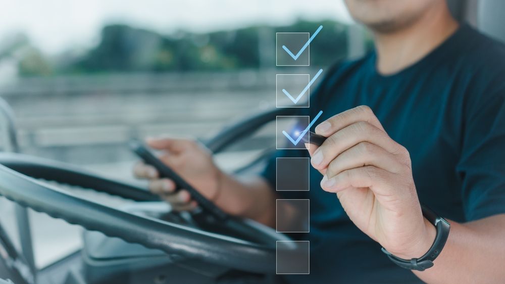 Person in truck using a checklist, marking items with a digital pen.