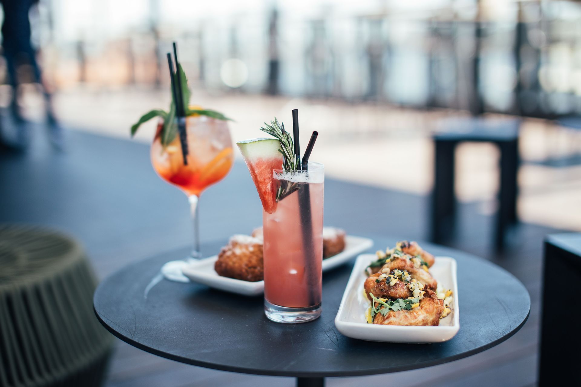 Tavolo da aperitivo elegante con cocktail, stuzzichini e atmosfera serale calda.