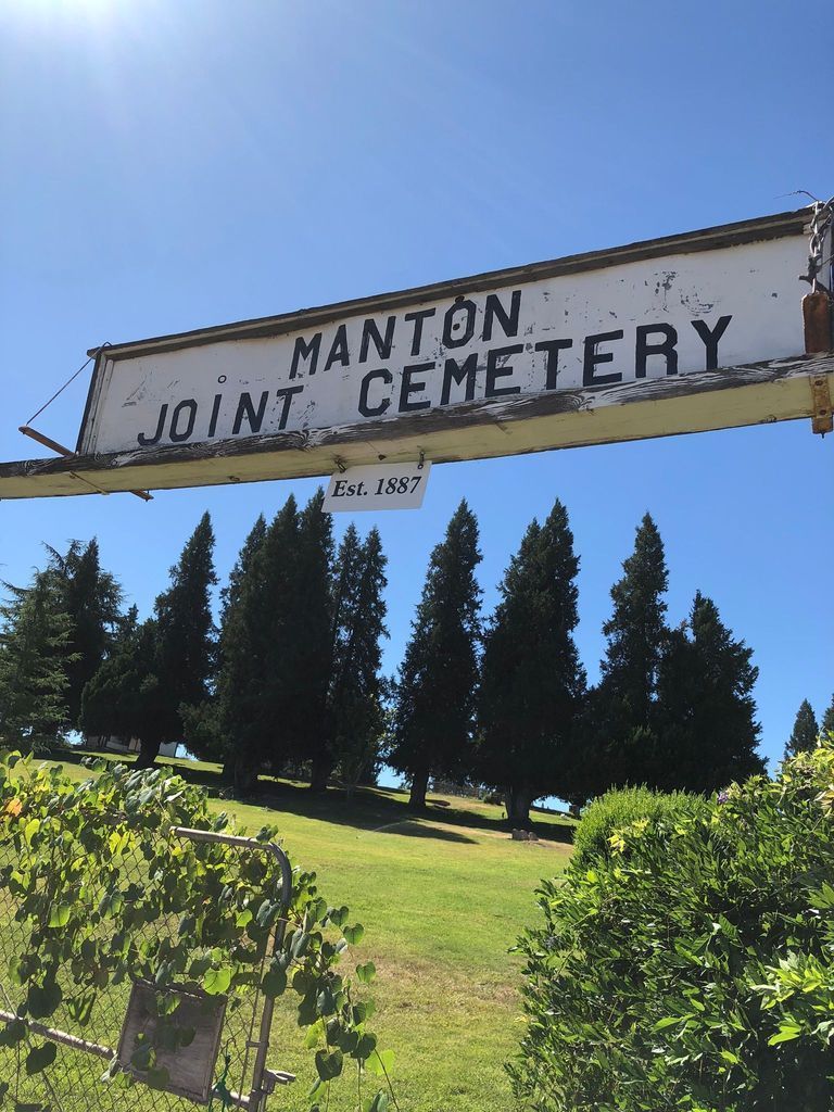 A sign for manton joint cemetery hangs over a grassy field