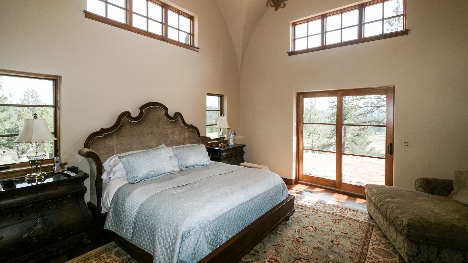 image of a bed in a room with large windows