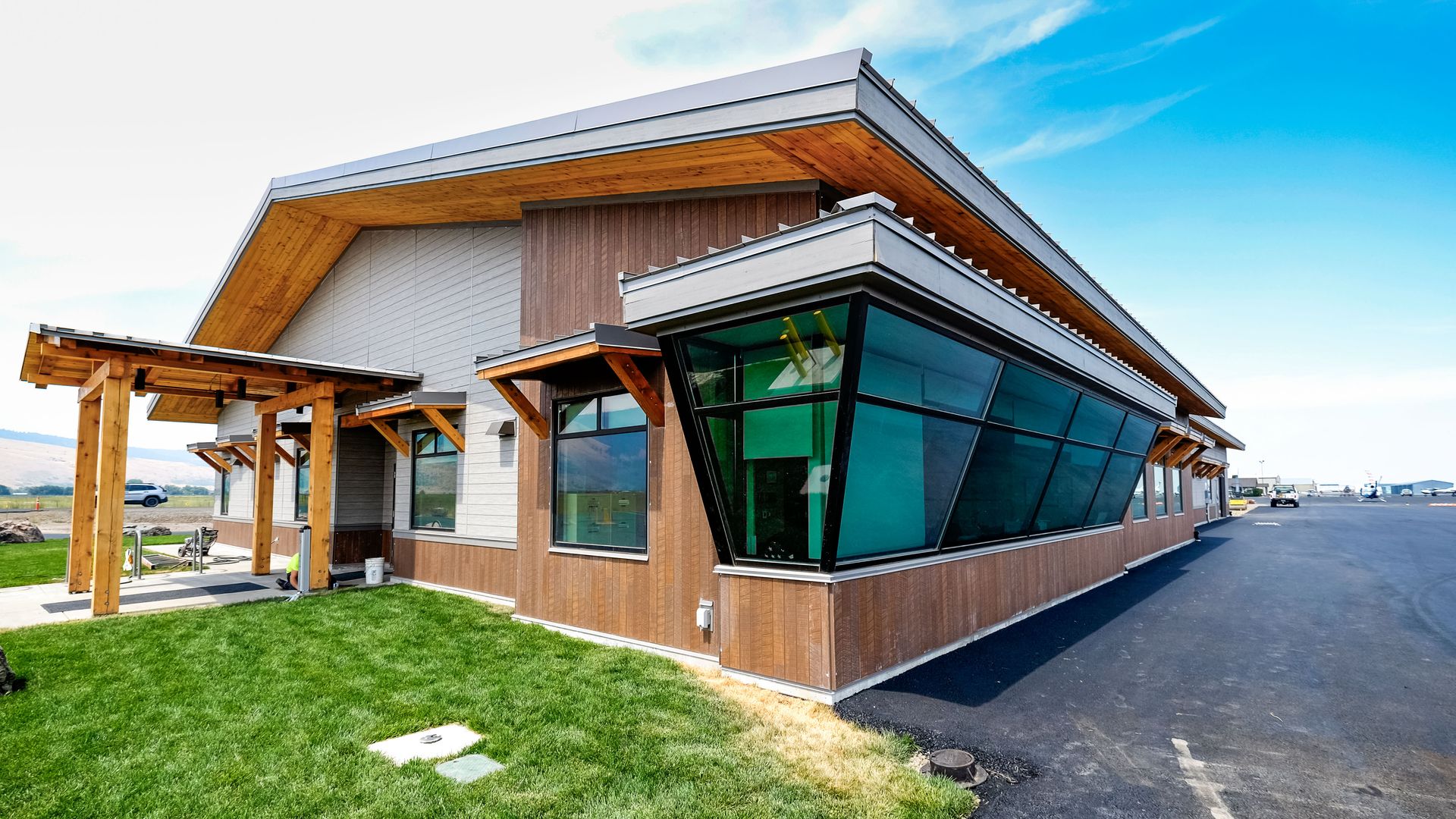a large building with a lot of windows and a wooden roof is sitting on top of a lush green field .
