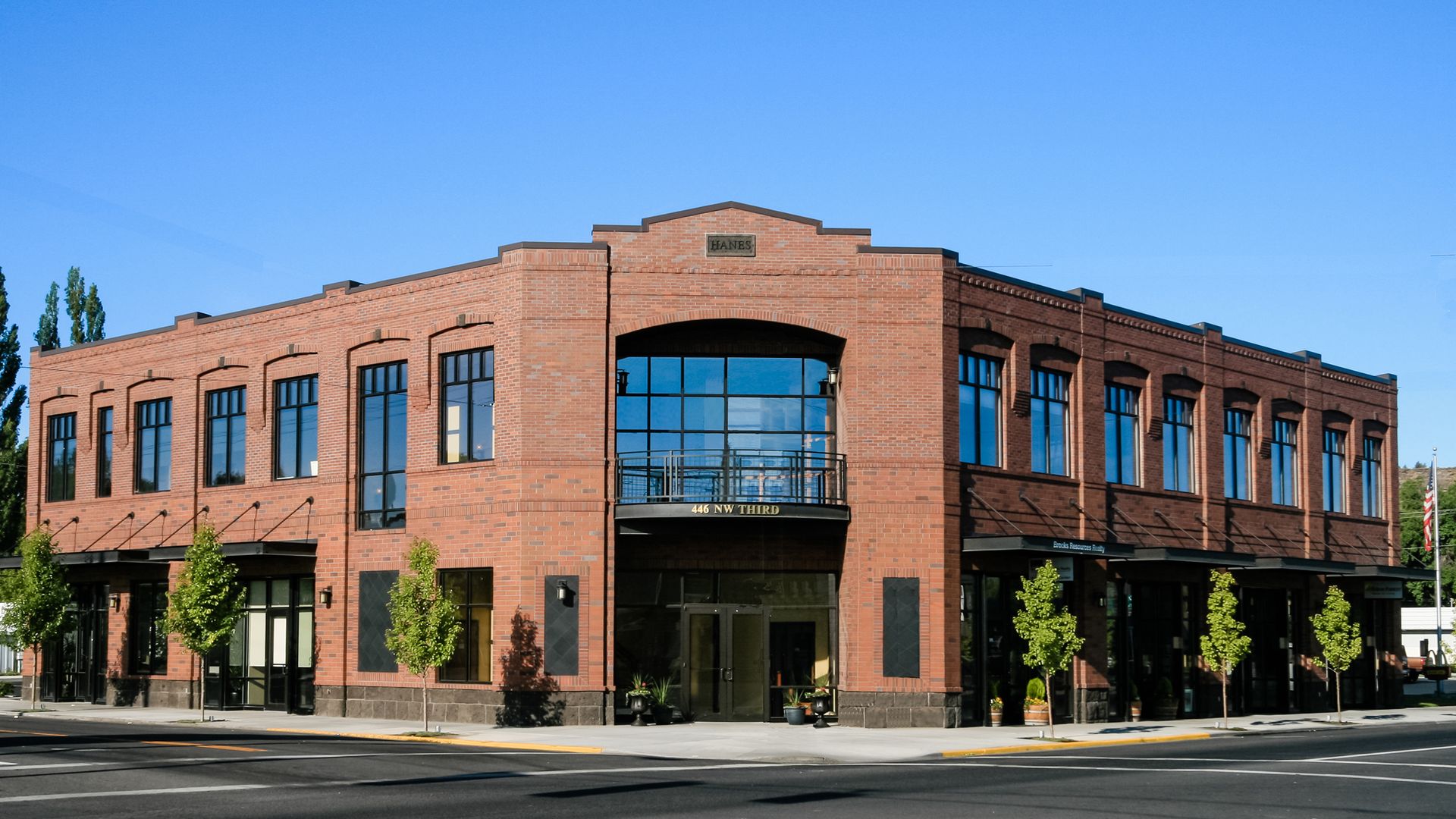 a large brick building with lots of windows is on the corner of a street .