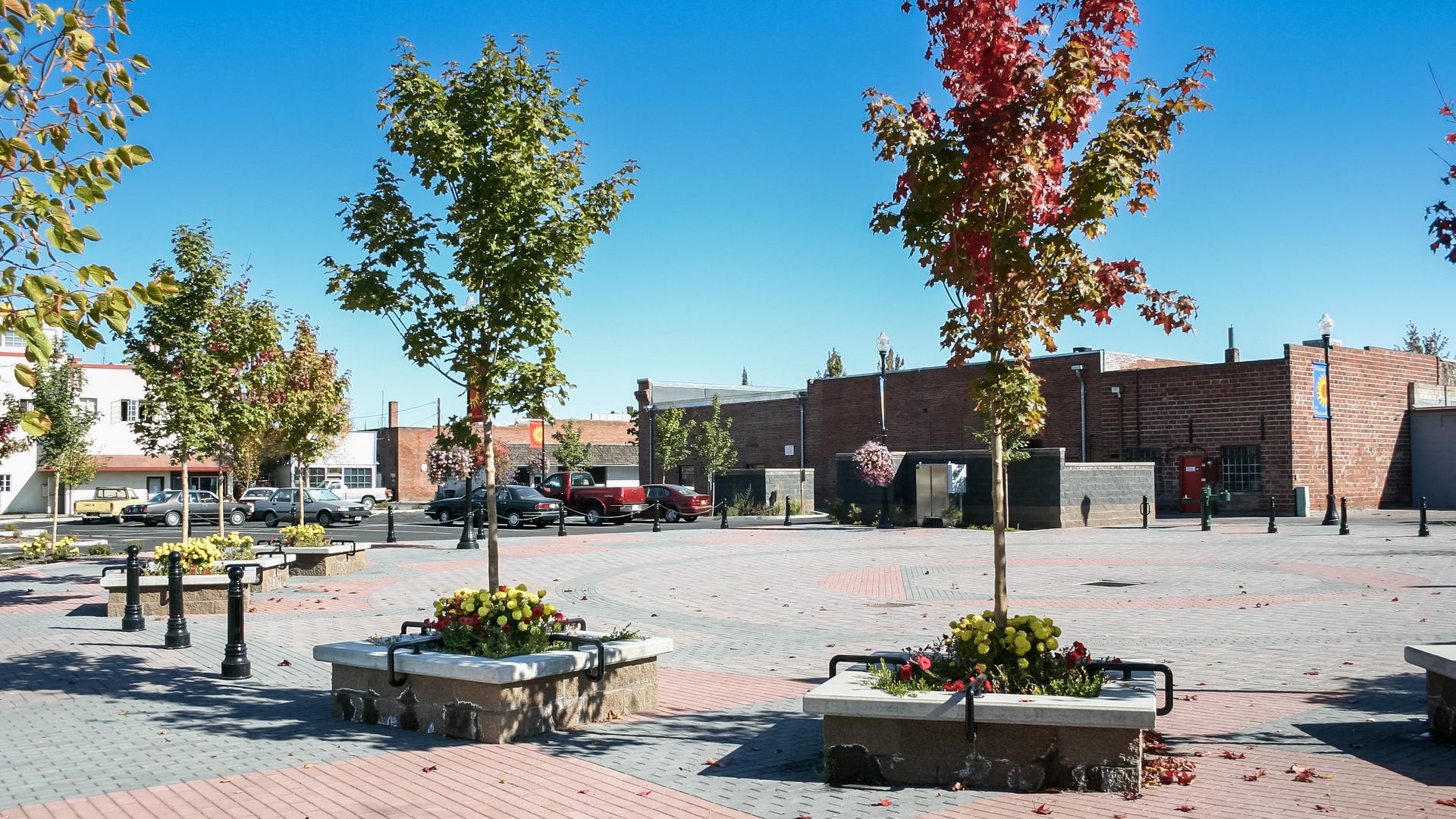 a brick square with trees and benches in front of a building