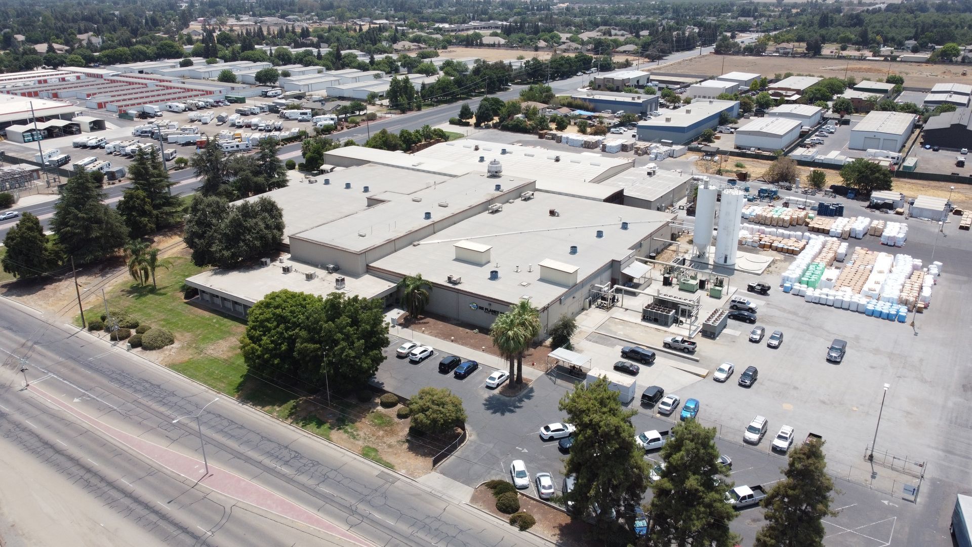 Aerial view of an industrial complex with multiple buildings, parking lot, and surrounding roads.