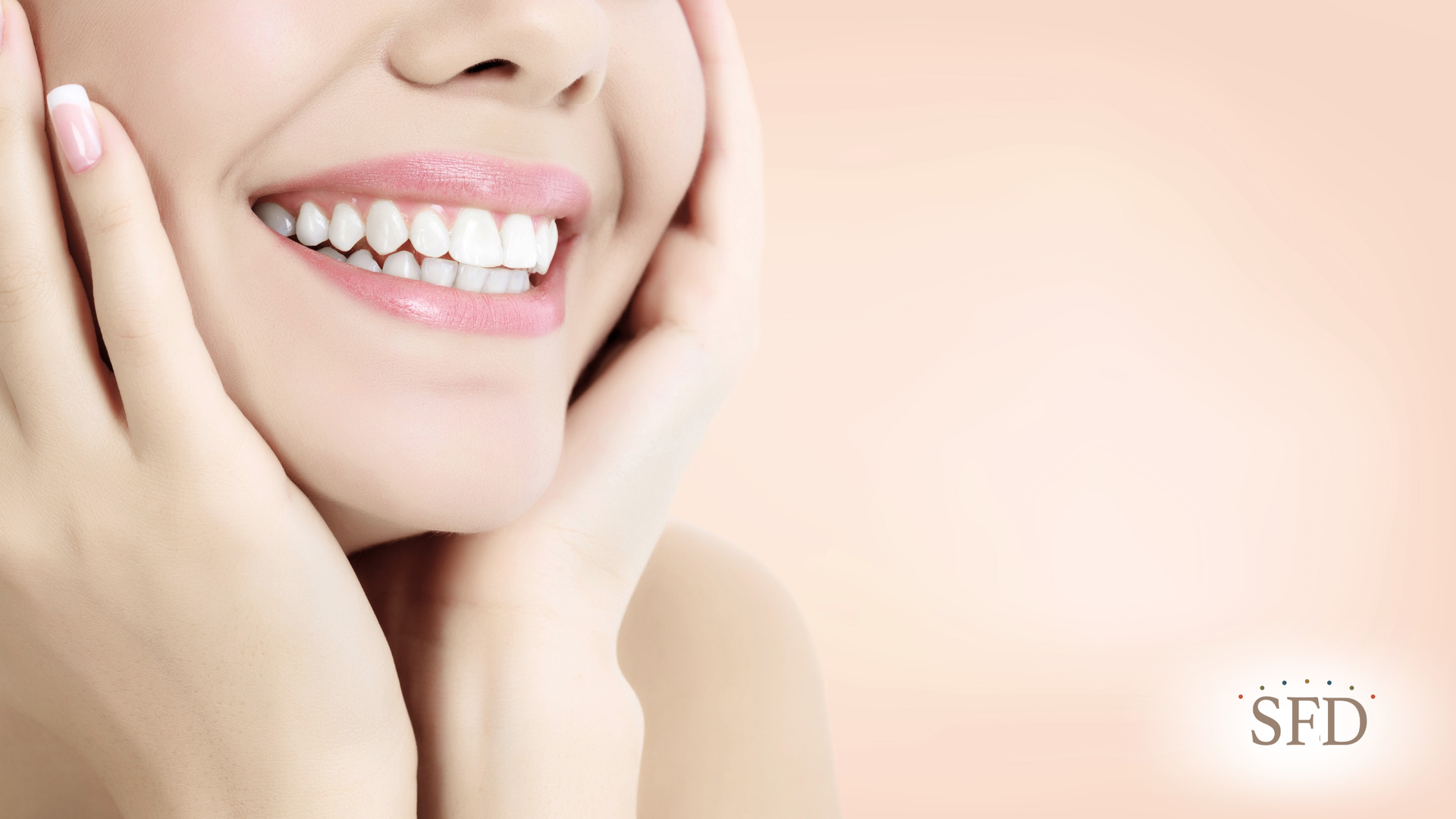 A woman is smiling with her hands on her face.