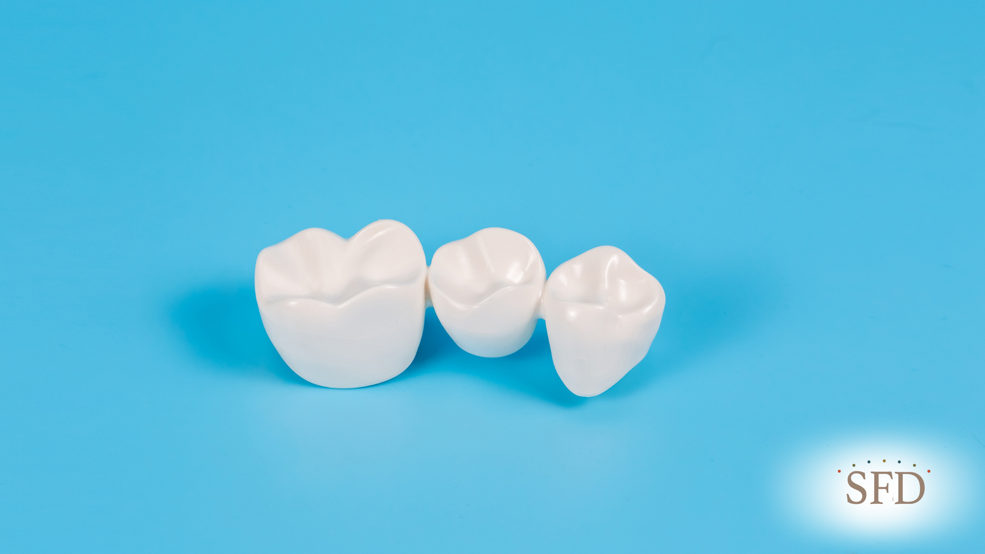 Three white dental crowns on a blue background.