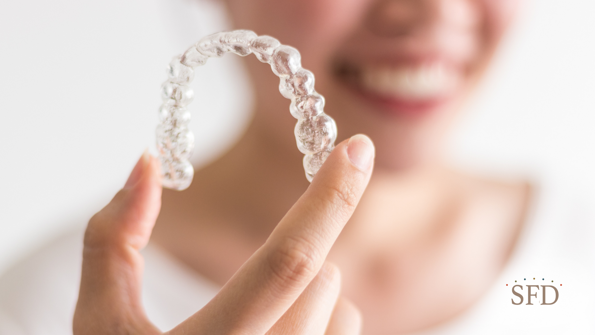 A woman is holding a clear brace on her finger.