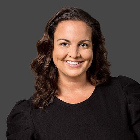 A woman in a black dress is smiling for the camera.