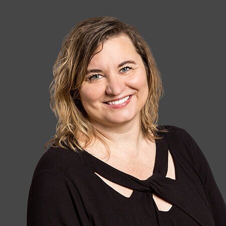 A woman in a black shirt is smiling for the camera.