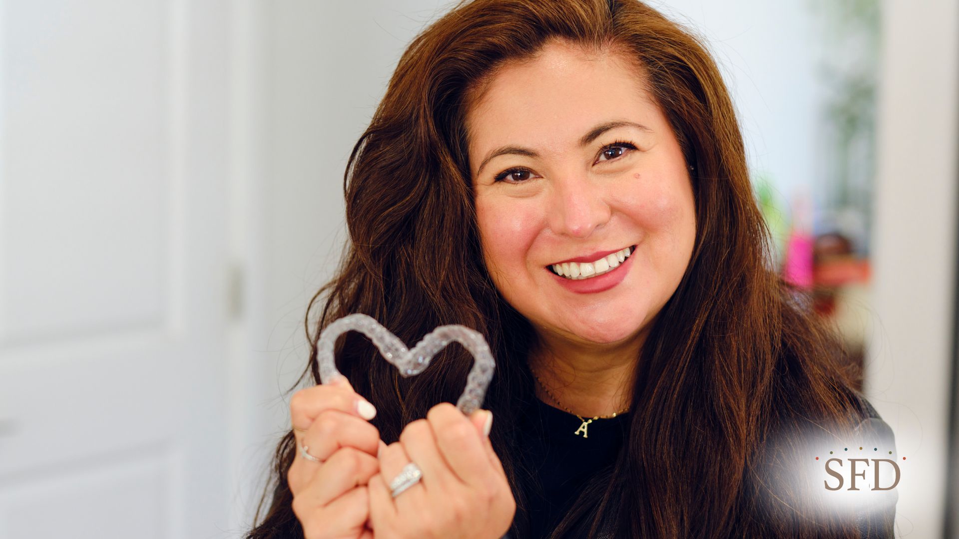 A woman is holding a heart shaped retainer in her hands.