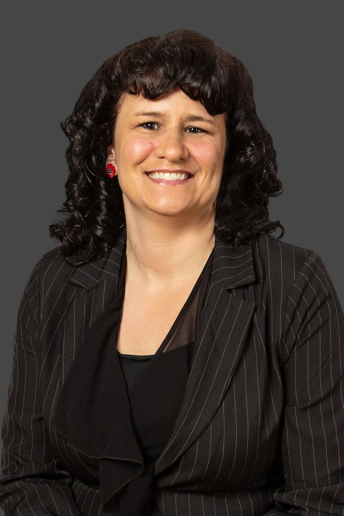 Portrait of a smiling woman in a black jacket against a gray background