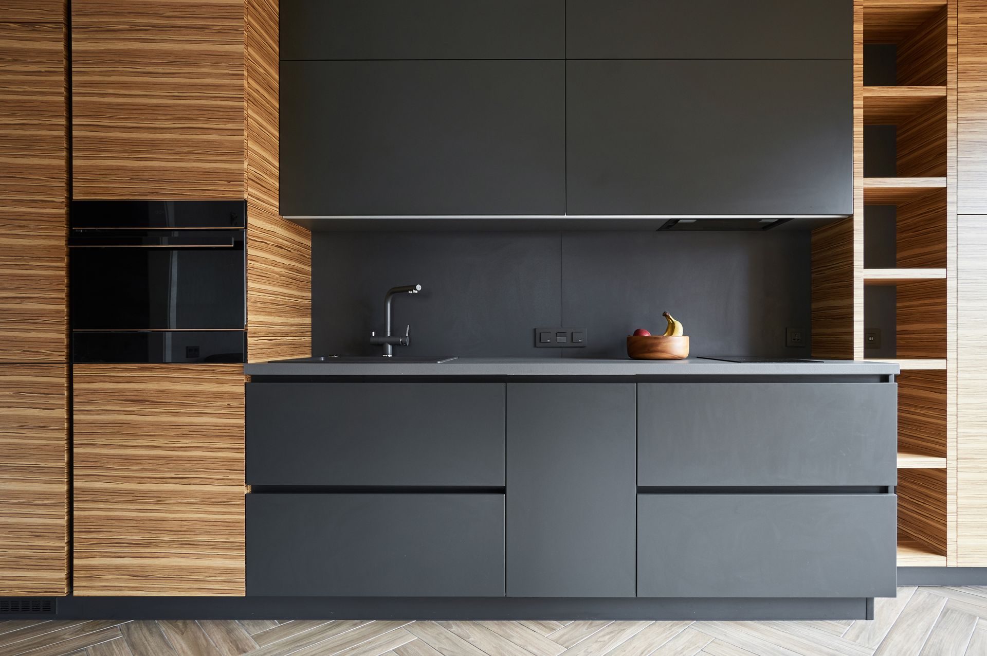 Modern kitchen with wooden paneling, gray cabinetry, and built-in oven.