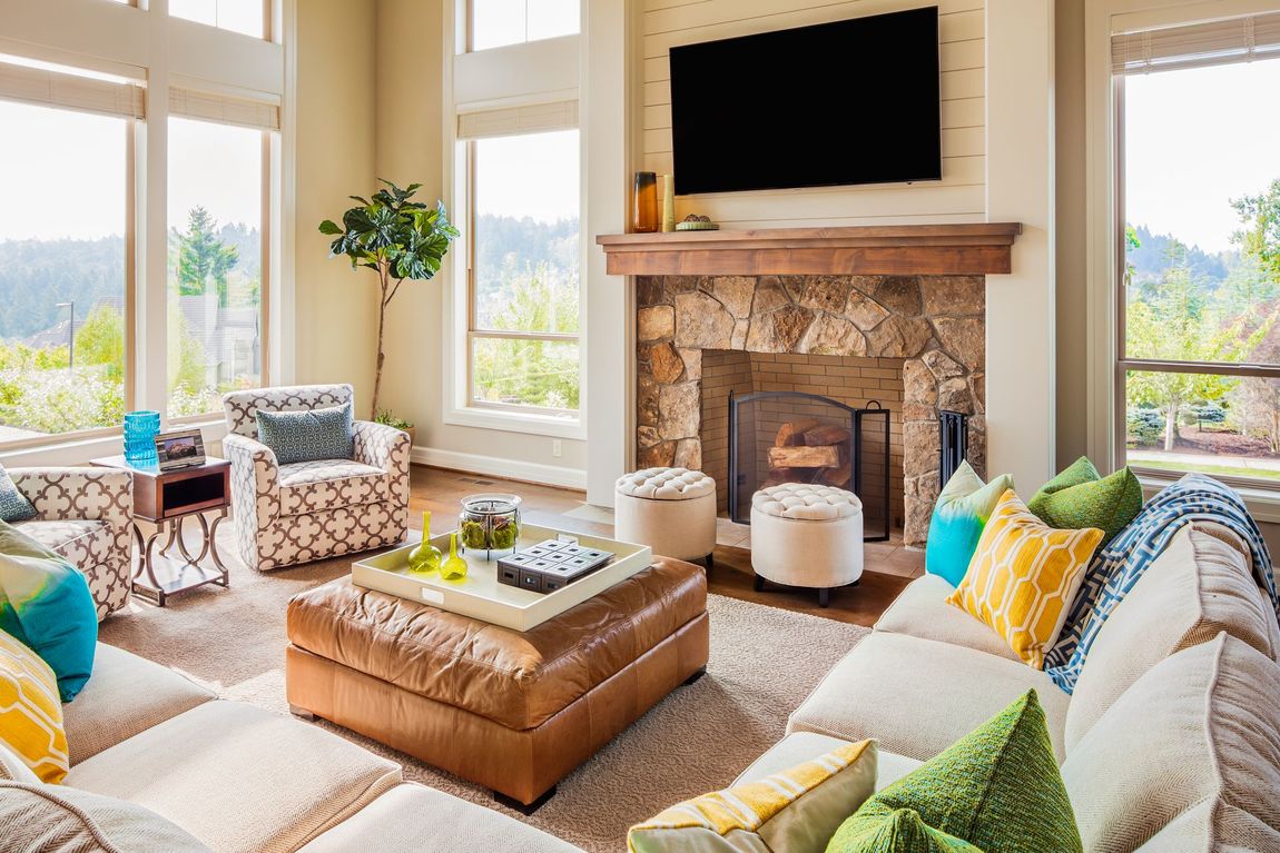 Spacious living room with sectional sofa, fireplace, large windows, and an ottoman coffee table.