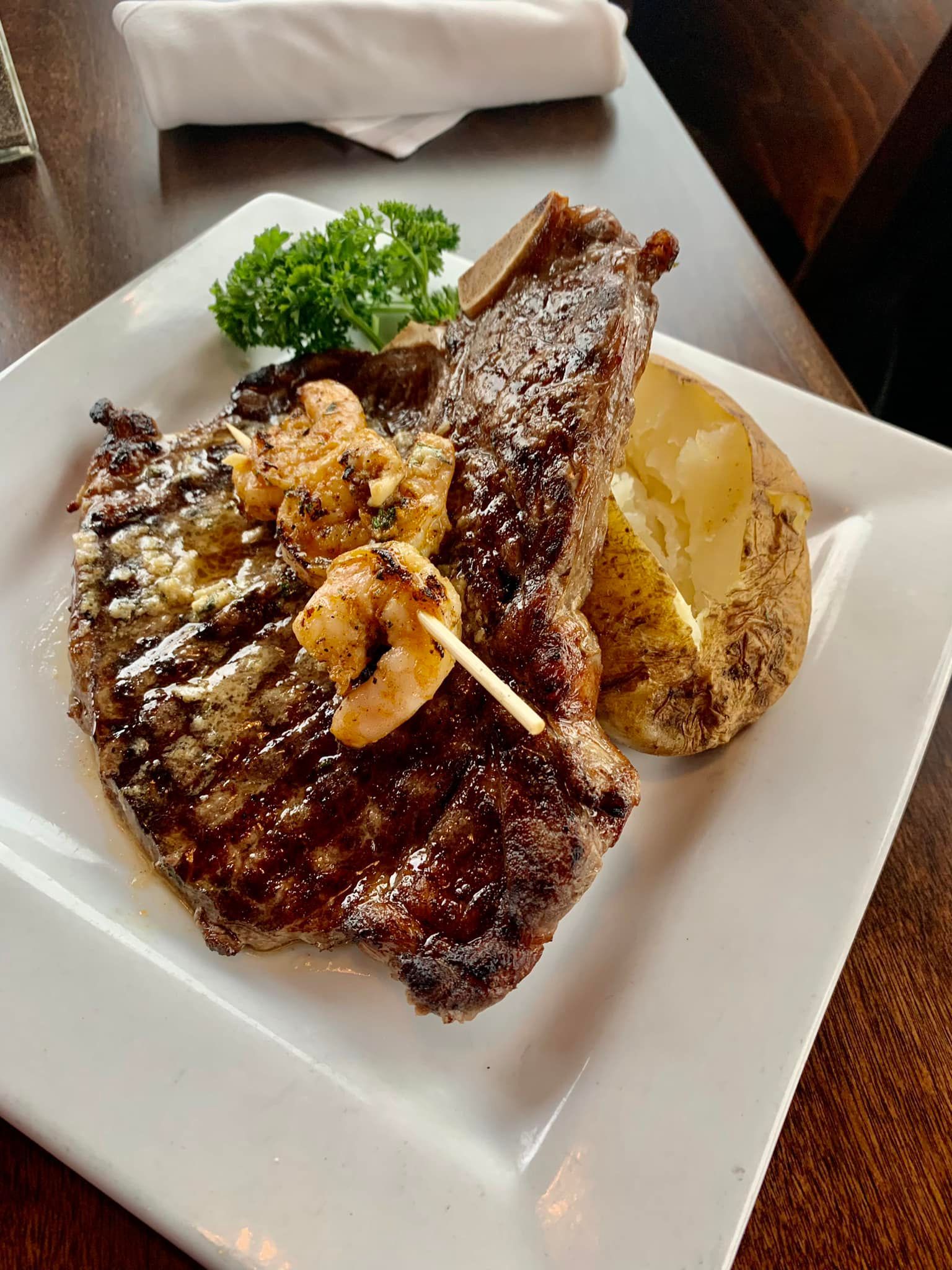 A steak with shrimp and potatoes on a white plate