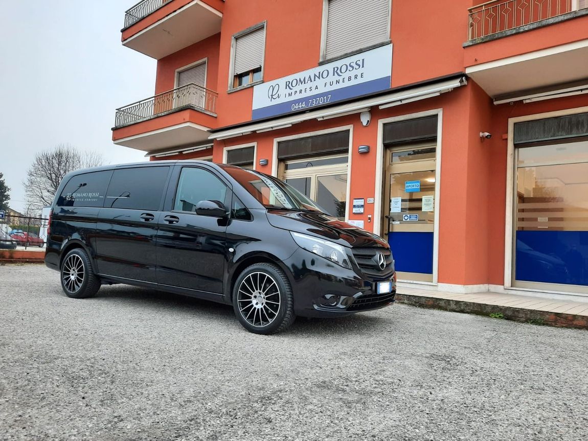 Un furgone per trasporto funebre è parcheggiato davanti a un edificio.