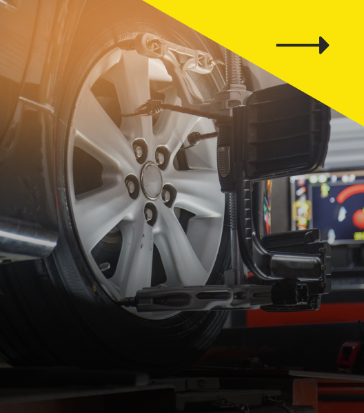 Car tire being aligned on a machine, with a computer screen in the background.