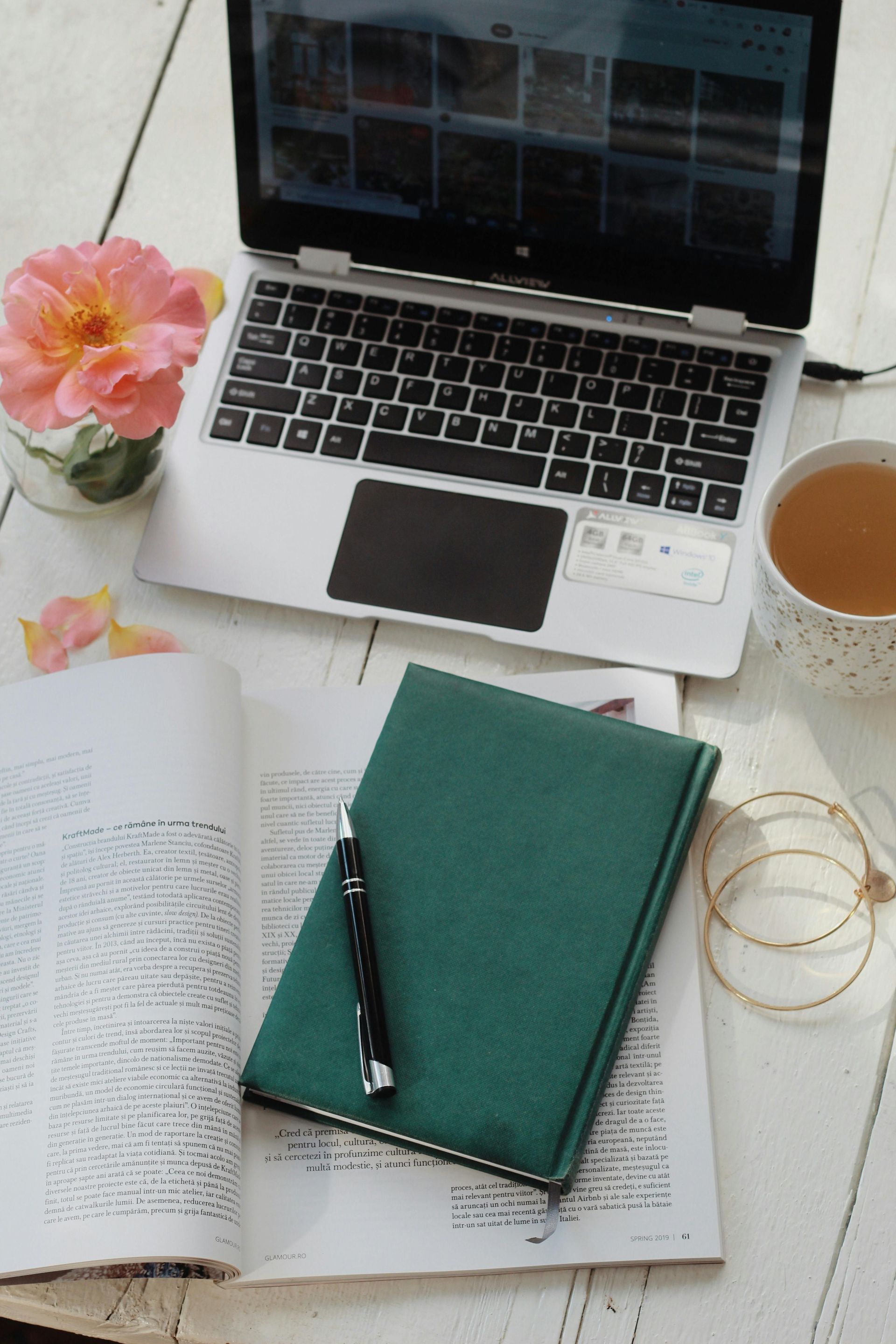 Laptop with pink flower beside it