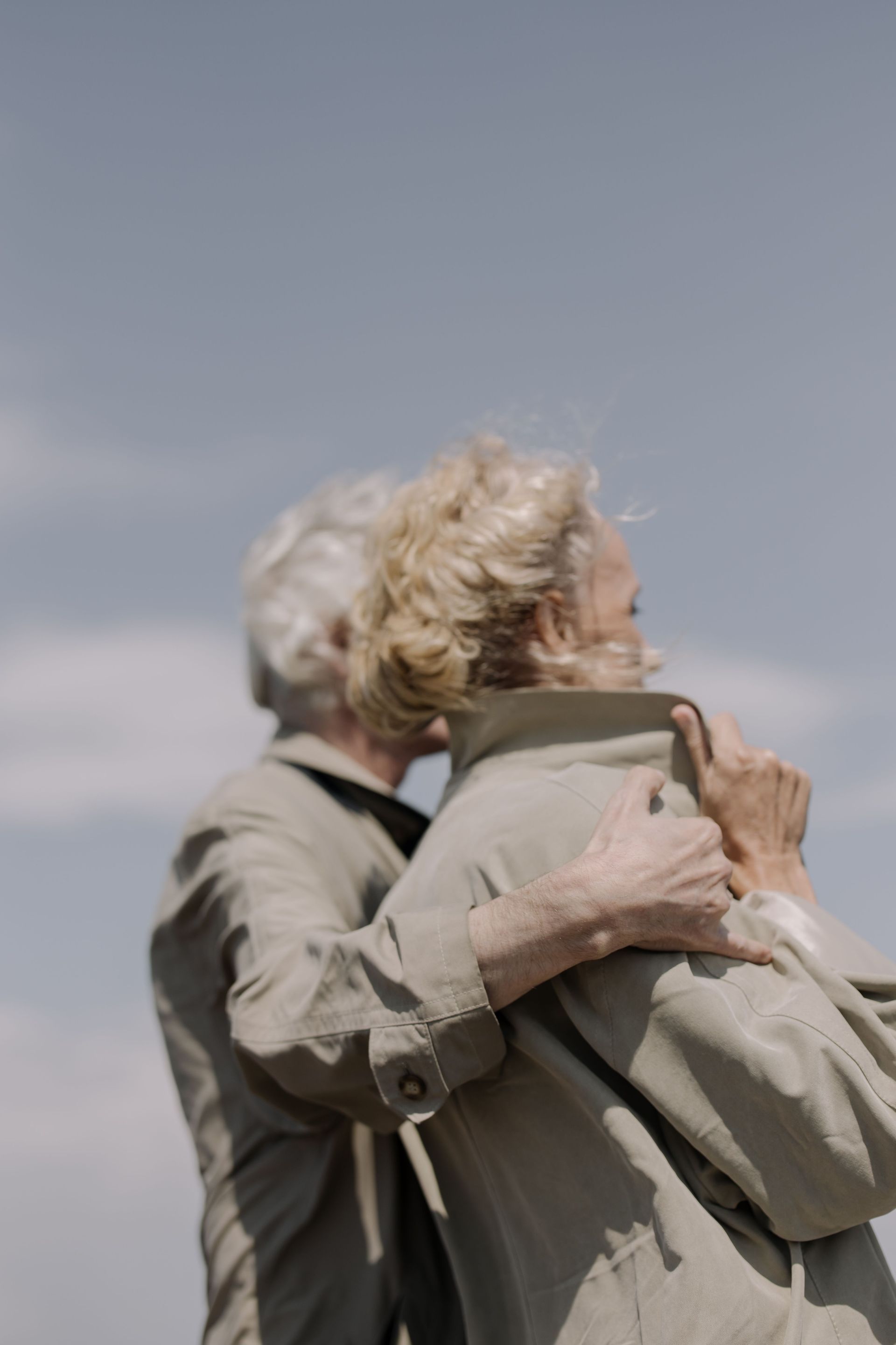 An older couple hugging each other and looking away (cannot see their faces)